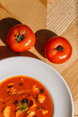 Tomato cream soup in a plate with tomatoes nearby. Italian cuisine with tomatoes
