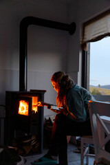 Fototapeta premium woman putting wood in fireplace cozy hygge living