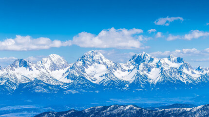 Obraz premium Panoramic view of majestic snow-capped mountains under vibrant blue sky adorned with fluffy white clouds, showcasing breathtaking winter alpine landscape