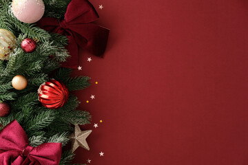 Christmas border with pine branch, bauble and velvet bow on red background, festive winter holiday...