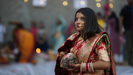 Newly married Indian woman offering coconut during Chhath Puja morning prayer, dressed in red saree symbolizing devotion, purity, and faith.