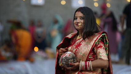 Indian bride performing Chhath Puja after marriage, holding coconut and diya during sunrise prayer, representing devotion and tradition.Smile