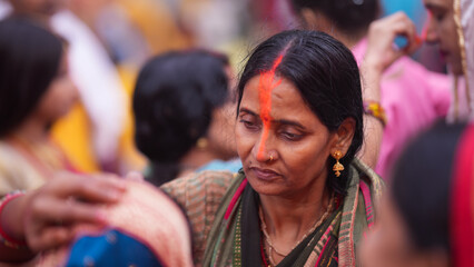 Devotee woman applying sindoor after completing Chhath Puja, symbolizing purity, devotion, and blessings after morning rituals.