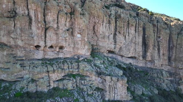 Aerial view of rugged rock formations with caves and crevices, the stone textures contrasting with sparse greenery, Apache Junction, Arizona, United States.