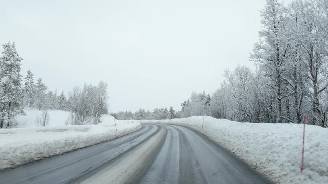 Car turning slowly on snowy forest road with clouds