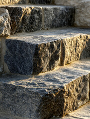 Detailed view of textured stone steps illuminated by warm sunlight showcasing rugged surfaces and natural architectural design in an outdoor setting