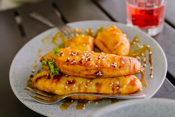 Sweet caramelized fried banana (Pisang Goreng) dessert, topped with glossy caramel sauce and served beautifully on a rustic wooden table