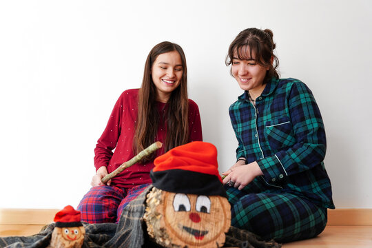 Girls celebrating Christmas tradition with Tio de Nadal log