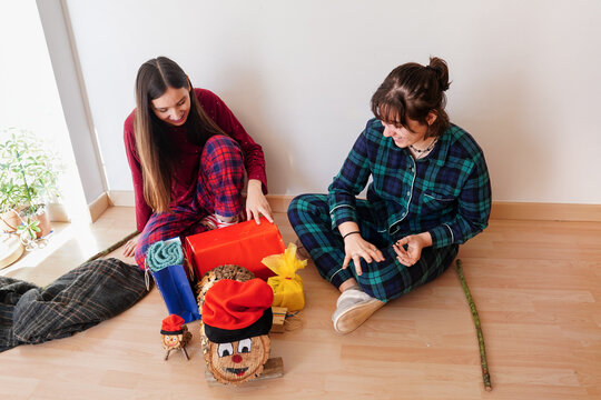 Girls opening presents with traditional Catalan Caga Tio log