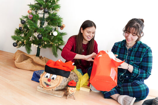 Couple of girls opening Christmas gifts with Caga Tio tradition