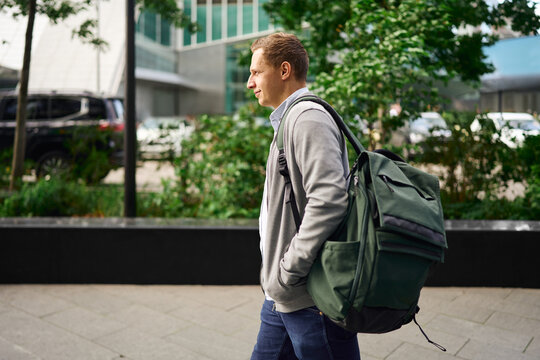 Man walking with backpack outdoors near office buildings