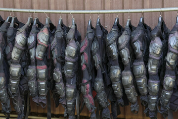 Row of black protective riot gear and armor suits hanging on rack. Police equipment prepared for...