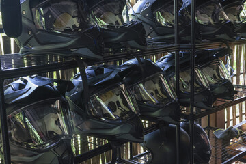 Black protective helmet and mask equipment stored on metal rack. collection of headgear ready for...