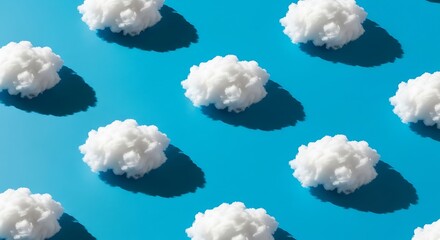 Repetitive arrangement of fluffy white cotton objects creates a stylized sky pattern against a bright blue background.