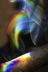 Mystical abstract background of colorful rainbow light shining through ethereal smoke from burning...