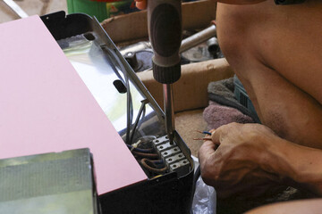 Close up of man hand using screwdriver for electronic repair. Focused person fixing broken...