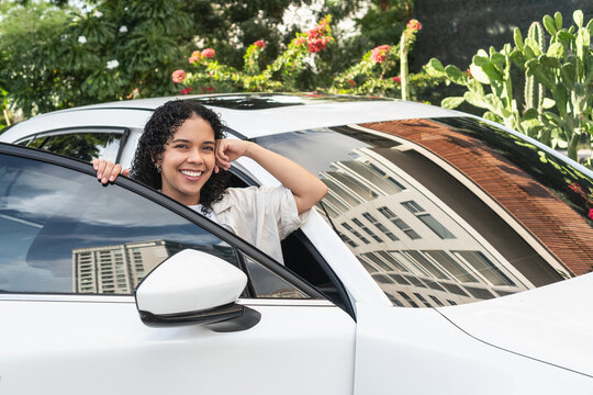 Happy young woman smiling from new car window