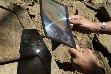 Focused hand holding fresnel lens, concentrating sunlight to create heat. An outdoor science...