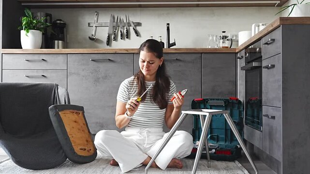 Frustrated young woman trying to assemble a chair with tools on the floor. Concept of difficulty and struggle in do it yourself project.