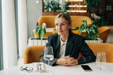 An attractive blonde business woman in a jacket is sitting in a cozy restaurant at a business...