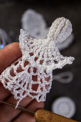 Close-up photo of crocheting a delicate white lace angel. Handmade eco-friendly Christmas...