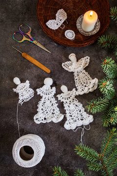 Close-up photo of crocheting a delicate white lace angel. Handmade eco-friendly Christmas decoration, slow life concept, and cozy winter mood.