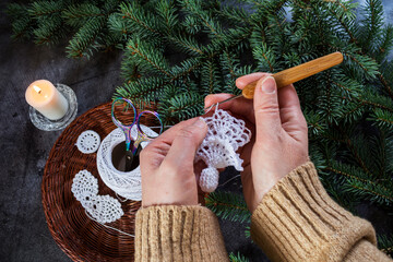 Female hands crocheting a lace angel ornament for Christmas. Cozy handmade process, eco-friendly...