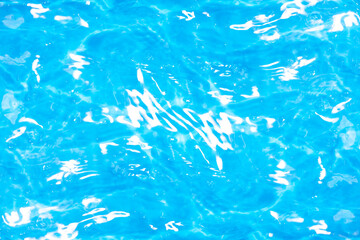 Blue water with ripples on the surface. Defocus blurred transparent blue colored clear calm water surface texture with splashes and bubbles. Water waves with shining pattern texture background.