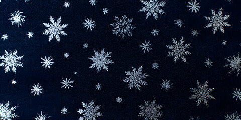 Abstract winter background features a repeating pattern of various-sized, sparkling, silvery snowflakes scattered across a dark navy blue backdrop, creating an elegant and festive texture.