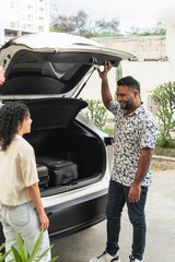 Couple packing luggage into car trunk for road trip