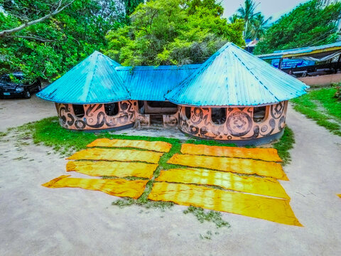 Aerial view of vibrant cloths laid to dry before an artistic building with conical roofs, surrounded by lush greenery, Ede, Osun, Nigeria.