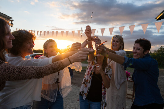 Friends cheering with sparklers at sunset celebration