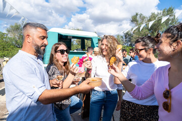 Friends sharing food and drinks at outdoor food truck party