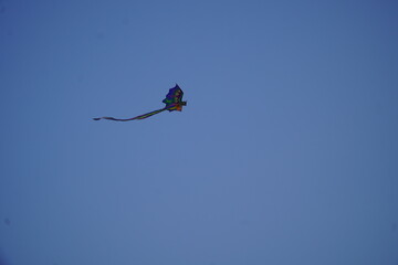 Fototapeta premium Colorful Kite Flying High in a Clear Blue Sky