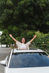 Happy woman enjoying freedom through car sunroof