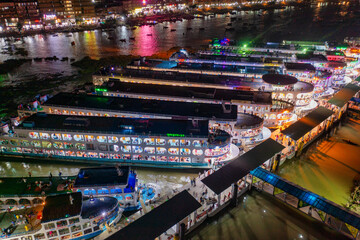 Aerial view of boats nestled along a pier, their lights reflecting on the water in a vibrant dance of color and movement, Dhaka, Dhaka Division, Bangladesh.
