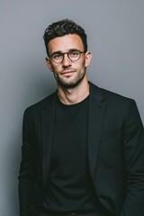 Obraz premium A confident young man with glasses dressed in a black blazer and black shirt.
