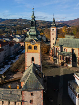 Aerial view of the vibrant hues of the Church of the Assumption of the Virgin Mary and Matej House under a crisp blue sky, Banska Bystrica, Banska Bystrica Region, Slovakia.