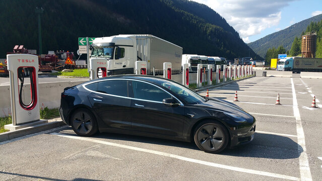 Brennero, Italy - June 23, 2020: A static shot of a solid black Tesla Model 3 dual motor long range awd charging at the Supercharger during summer. No other cars