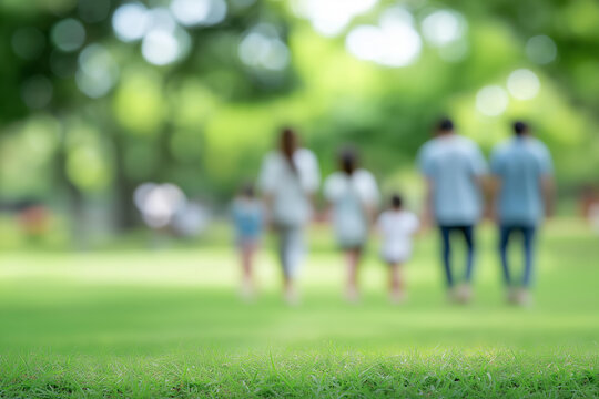 Multiple generations on grass with defocused park background, faceless family gathering, outdoor celebration visualization, blurred green scene, togetherness detail, multi-age bond