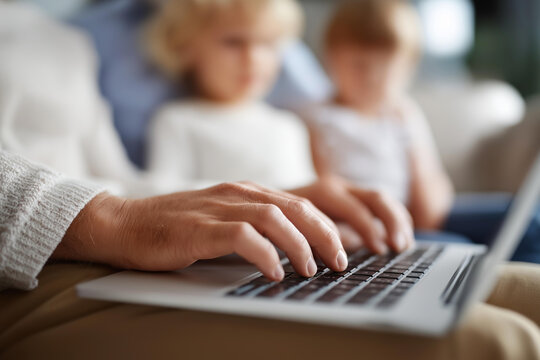 Hands on laptop keyboard with family gathered and defocused couch, faceless technology time, home activity visualization, blurred living room, digital bonding detail, family entert