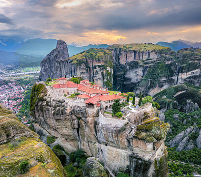 Aerial view of the monasteries perched atop the colossal rock formations, bathed in the warm glow of the setting sun, Meteora, Kalabaka, Trikala, Greece.