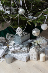 Steel-colored gift boxes paired with glowing candles and delicate decorations under a lush Christmas tree, creating an elegant and festive holiday atmosphere