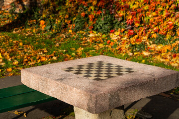 Chess table with built-in chessboard located in a green park. Symbol of intelligence, strategy, and recreation in nature. Perfect for lifestyle, relaxation, and outdoor activities themes.