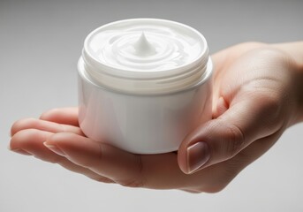 Hand holding a jar of white cosmetic cream for skincare and beauty