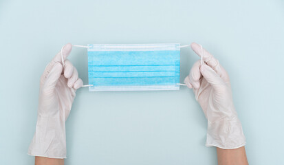 Hands wearing disposable gloves holding a mask