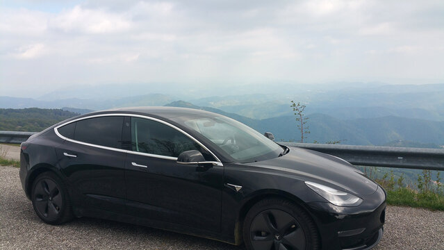 Savogna, Italy - May 04, 2020: Matajur Mountain, a static shot of a solid black Tesla Model 3 dual motor long range awd with tinted windows and aero wheels in a cloudy spring day