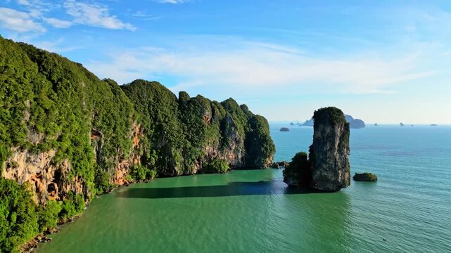 Aerial view of towering limestone cliffs, lush green vegetation, and turquoise waters creating a striking contrast of textures and colors, Ao Nang, Krabi, Thailand.