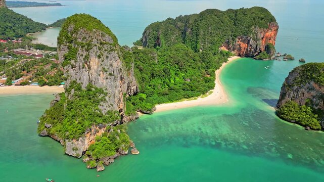 Aerial view of Railay Beach's turquoise waters contrasting with the rugged limestone cliffs covered in lush greenery, creating a tropical paradise, Ao Nang, Krabi, Thailand.