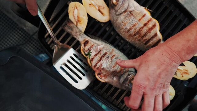 Fresh bream fish on bbq, stuffed with lemon and dill. Outdoor barbecue cooking in summer, seafood grill.
Patatoes with garlic.